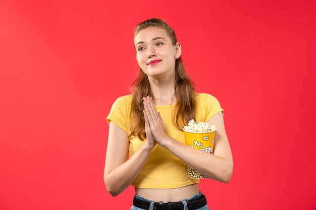 Widok Z Przodu Młoda Kobieta Trzyma Pakiet Popcornu I Pozuje Na Jasnoczerwonej ścianie Kino Film Kinowy