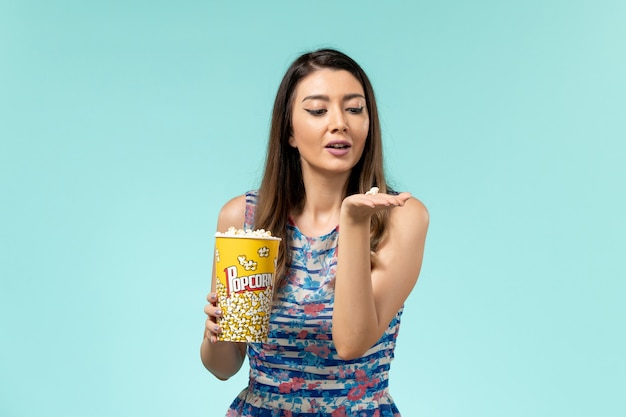 Widok z przodu młoda kobieta trzyma pakiet popcornu na niebieskim biurku