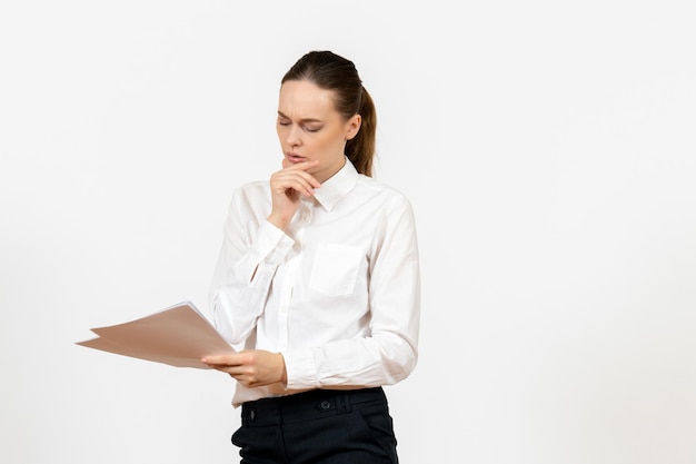 Widok z przodu młoda kobieta w białej bluzce trzymająca i czytająca dokumenty na białym tle kobiece uczucie pracy emocja biuro