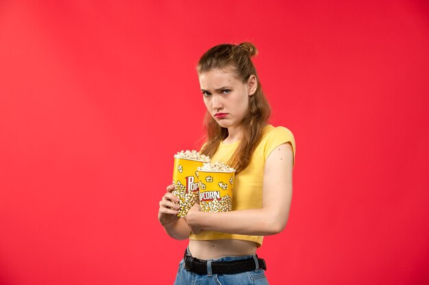 Widok z przodu młoda kobieta w kinie trzymając pakiety popcornu na jasnoczerwonej ścianie kino kino kobiece film zabawa