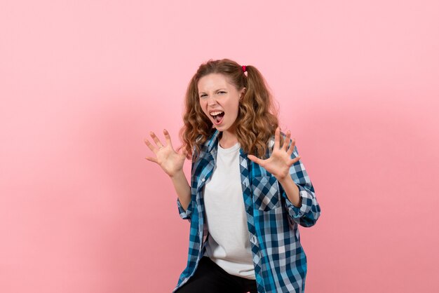 Widok z przodu młoda kobieta w niebieskiej koszuli w kratkę krzyczy na różowym tle emocje młodzieży dziewczyna model moda dzieciak