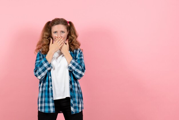 Widok z przodu młoda kobieta w niebieskiej kraciastej koszuli zakrywającej usta na różowej ścianie kobieta dziecko młodzież model kolor emocje