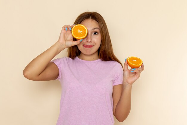 Widok z przodu młoda kobieta w różowej koszulce i dżinsach, trzymając pomarańczowe kawałki