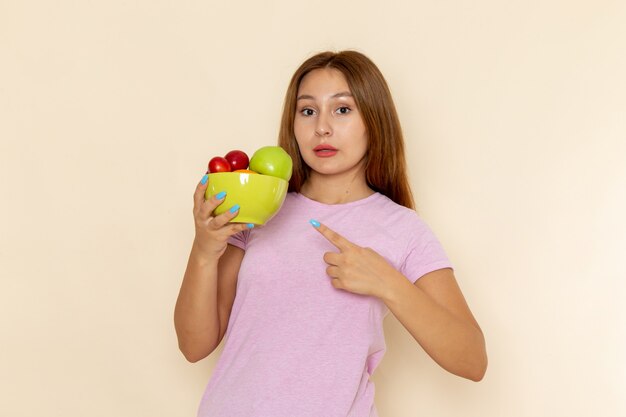 Widok z przodu młoda kobieta w różowej koszulce i dżinsach trzymając talerz z owocami