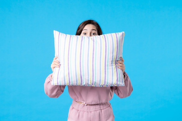 Bezpłatne zdjęcie widok z przodu młoda kobieta w różowej piżamie trzymająca poduszkę na niebieskiej ścianie noc kolor łóżko odpoczynek emocje sen kobieta sen bezsenność