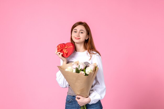 Widok z przodu młoda kobieta z kwiatami i prezent jako prezent na dzień kobiet na różowym tle róża poziomy marsz kobieca randka kobieta kocha zmysłową równość