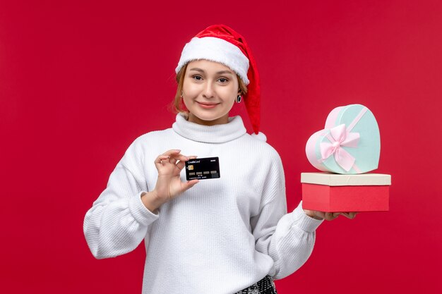 Widok z przodu młoda kobieta z prezentami i kartą bankową na czerwonym tle