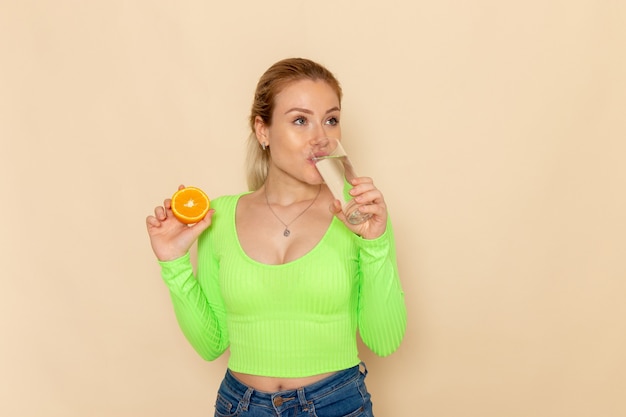 Widok Z Przodu Młoda Piękna Kobieta W Zielonej Koszuli Trzyma Pomarańczowy Plasterek I Szklankę Wody Pitnej Na ścianie Kremu Owoc Model Kobieta Mellow