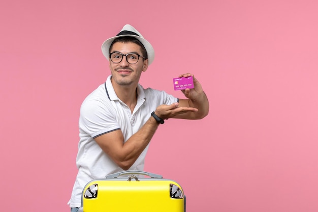 Bezpłatne zdjęcie widok z przodu młodego mężczyzny trzymającego fioletową kartę bankową na letnie wakacje na różowej ścianie