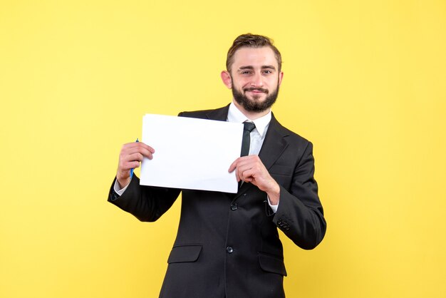 Widok z przodu młodego mężczyzny w czarnym garniturze, wesoło uśmiechnięty i trzymający białe puste kartki papieru na żółto