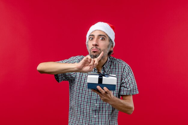 Widok z przodu młodego mężczyzny z prezentem świątecznym na czerwono