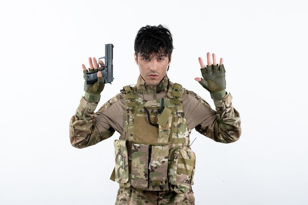 Widok z przodu młodego żołnierza w kamuflażu z białą ścianą pistoletu