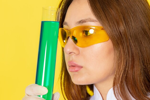 Widok z przodu młodej chemik kobiet w białym garniturze, trzymając roztwory chemiczne