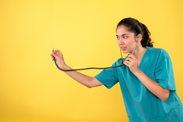 Widok Z Przodu Młodej Lekarki Trzymając Stetoskop Na żółtej ścianie