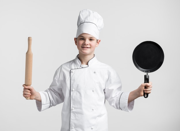 Widok z przodu młody chłopak przebrany za szefa kuchni gospodarstwa narzędzi