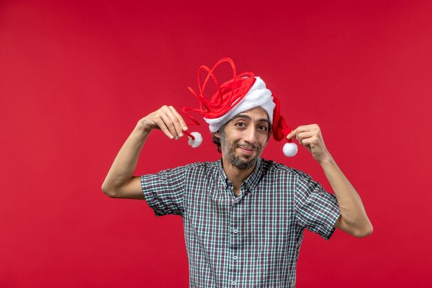 Widok z przodu młody człowiek ubrany w czapkę śmieszne zabawki na czerwonej ścianie