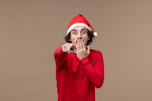 Widok z przodu młody człowiek z wstrząśniętą twarzą na brązowym tle świąteczne emocje Boże Narodzenie