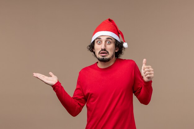 Widok z przodu młody człowiek z zmieszaną twarzą na brązowym tle świąteczne emocje Boże Narodzenie