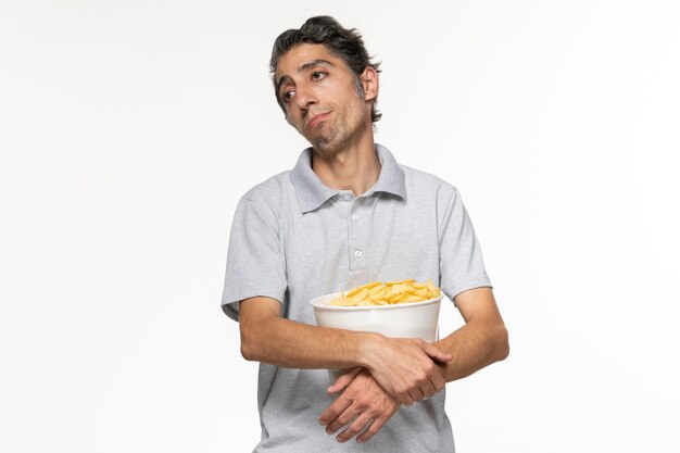Widok z przodu młody mężczyzna jedzący chipsy ziemniaczane podczas oczekiwania na zakończenie filmów na białej powierzchni