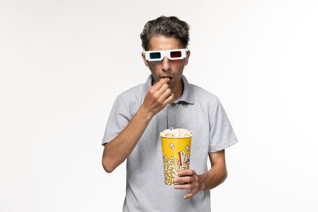 Widok z przodu młody mężczyzna jedzenie popcornu d okulary przeciwsłoneczne na białej powierzchni