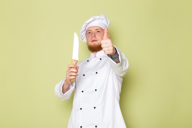 Widok z przodu młody mężczyzna kucharz w białym garniturze kucharz biały kapelusz gospodarstwa nóż