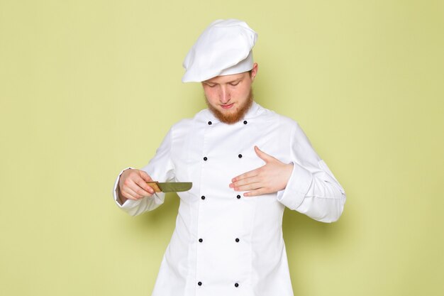 Widok z przodu młody mężczyzna kucharz w białym garniturze kucharz biały kapelusz gospodarstwa nóż
