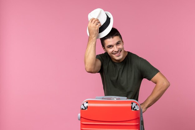 Widok z przodu młody mężczyzna na wakacjach w kapeluszu i uśmiechający się na różowej przestrzeni