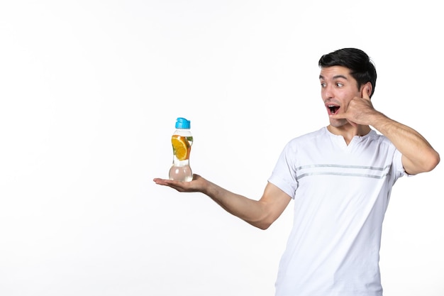 Widok z przodu młody mężczyzna trzymający butelkę lemoniady na białym tle sok świeży napój skóra owoce poziome chłodzenie lód ludzki płyn