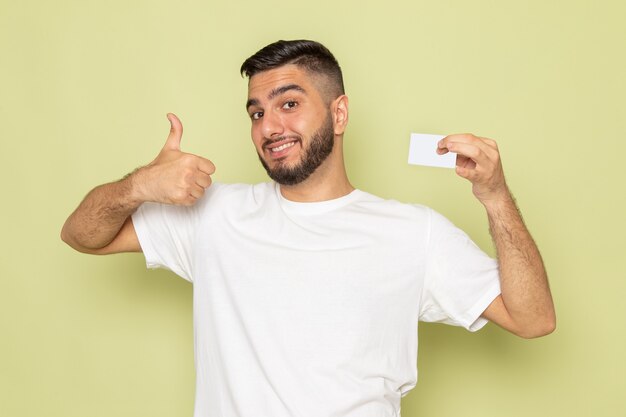 Widok z przodu młody mężczyzna w białej koszulce uśmiecha się i trzyma białą kartę