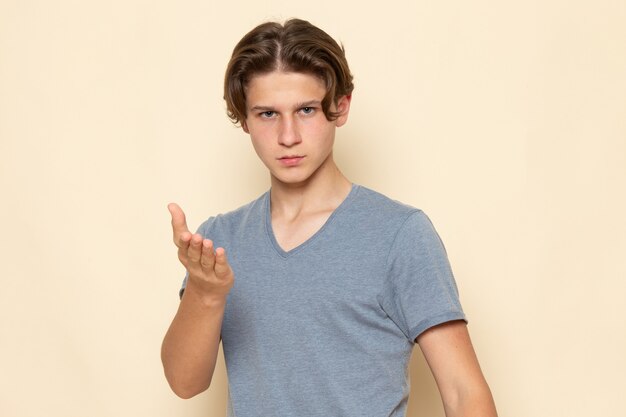 Widok z przodu młody mężczyzna w szarej koszulce pozuje z gestami