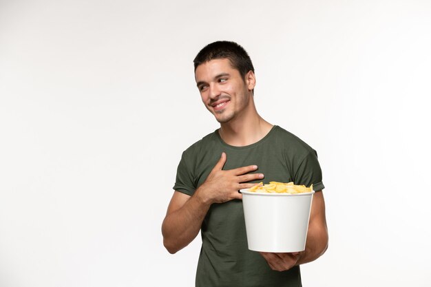 Widok z przodu młody mężczyzna w zielonej koszulce z ziemniaczanymi żetonami uśmiechnięty na białej ścianie film osoba mężczyzna samotny kino filmowe