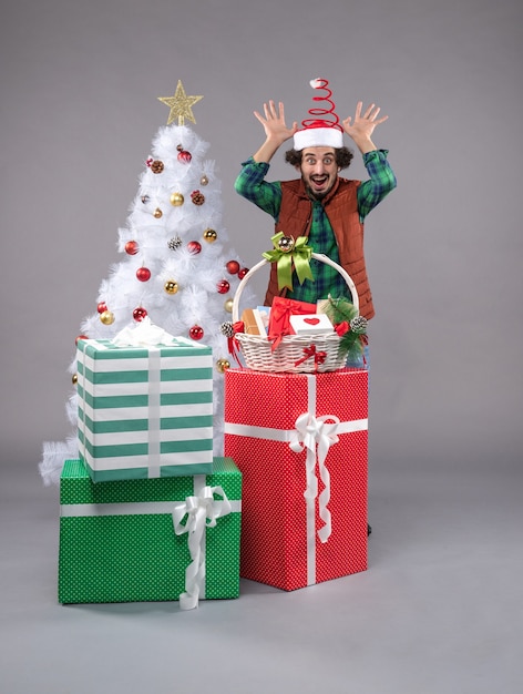 Bezpłatne zdjęcie widok z przodu młody mężczyzna wokół świątecznych prezentów na lekkiej podłodze ludzki świąteczny prezent nowy rok