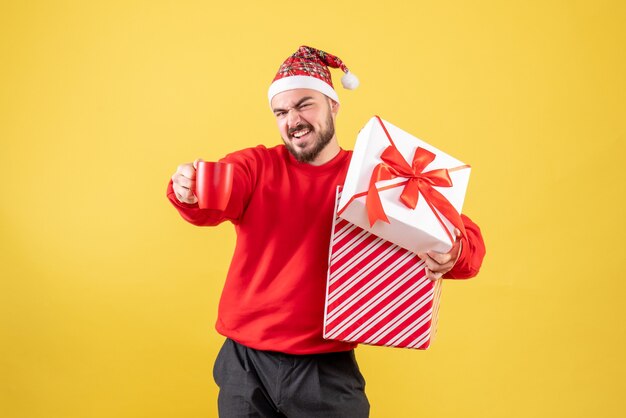 Widok z przodu młody mężczyzna z prezentem xmas i filiżanką herbaty na żółtym tle