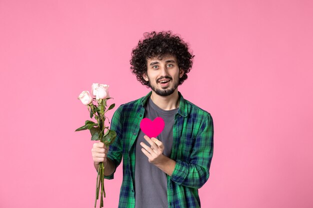 Widok z przodu młody mężczyzna z różowymi różami i naklejką z sercem na różowo