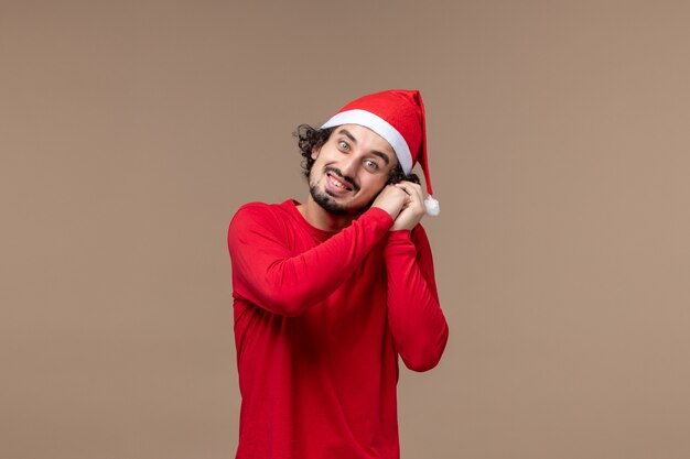 Widok z przodu młody mężczyzna z uśmiechem na twarzy na brązowym tle emocji świąt Bożego Narodzenia