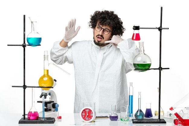 Widok z przodu młody naukowiec mężczyzna w białym specjalnym garniturze stojący wokół stołu z rozwiązaniami