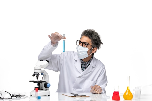 Widok z przodu naukowiec w średnim wieku w specjalnym garniturze siedzi trzymając kolbę z roztworem