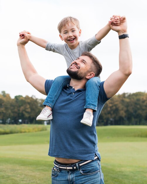 Widok z przodu ojca trzymającego syna na ramionach