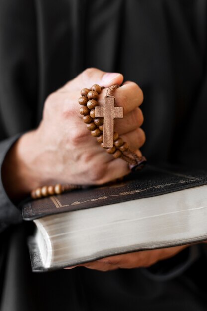 Widok z przodu osoby trzymającej różaniec z krzyżem i świętą księgą