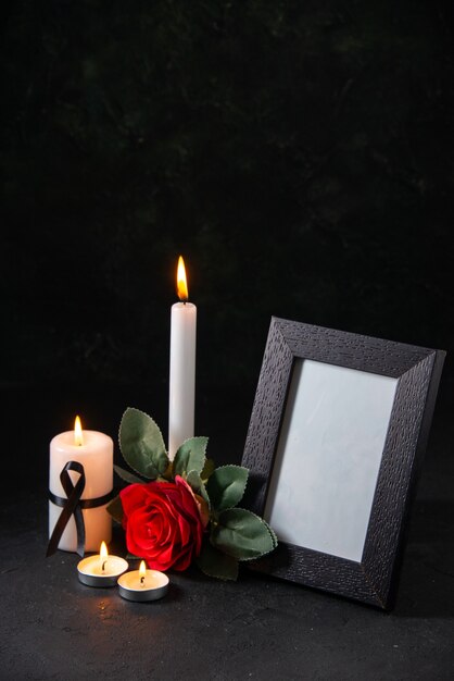 Widok z przodu płonącą świecę z ramką na zdjęcie i kwiatem na ciemnej powierzchni