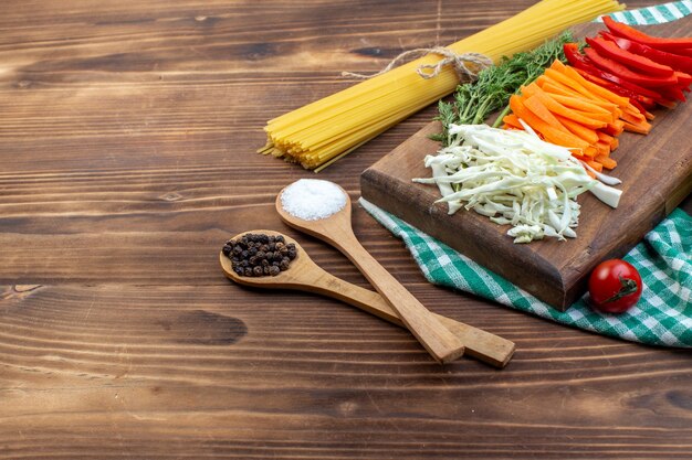 Widok z przodu pokrojone warzywa kapusta, marchewka, papryka na brązowej powierzchni deski do krojenia