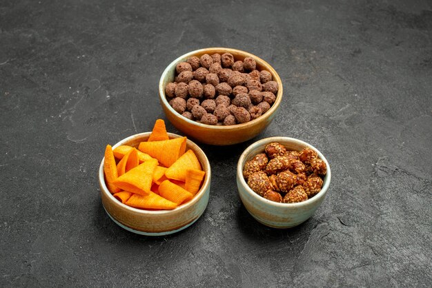 Widok z przodu pomarańczowe cipsy ze słodkimi orzechami i płatkami na szarym tle przekąska posiłek śniadanie orzech