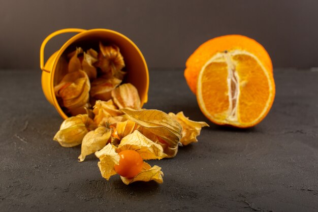 Widok z przodu pomarańczowe owoce ze skórkami wraz z plasterkami i całą pomarańczą na ciemno