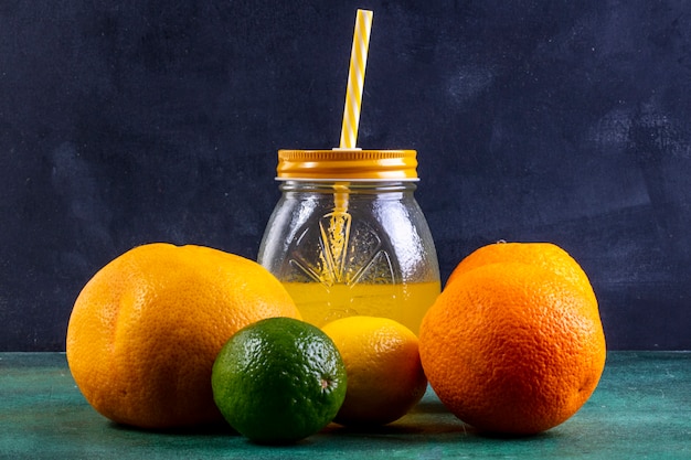 Bezpłatne zdjęcie widok z przodu pomarańczy z limonką i sokiem pomarańczowym w słoiku