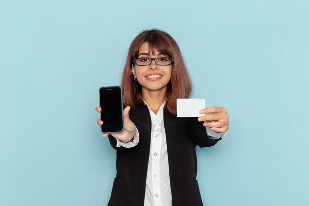 Widok z przodu pracownica biurowa w ścisłym garniturze trzyma białą kartę i telefon na niebieskiej powierzchni