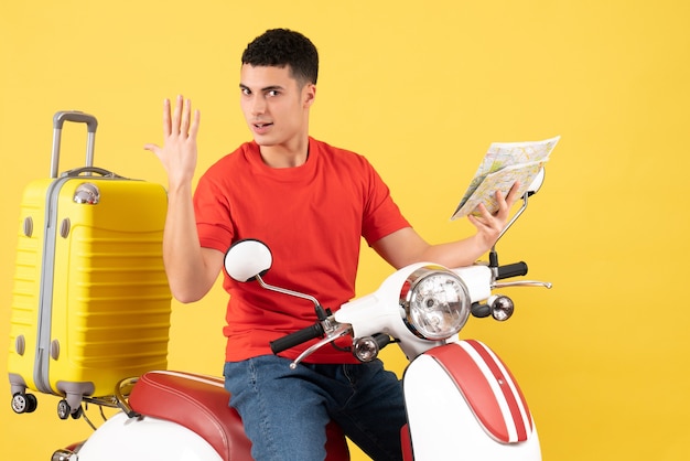 Widok z przodu przystojny młody człowiek na motorowerze z walizką trzymając mapę