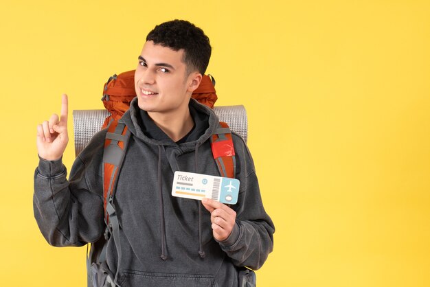 Widok z przodu przystojny podróżnik mężczyzna z plecakiem trzymając bilet, wskazując na sufit