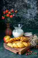 Bezpłatne zdjęcie widok z przodu pyszne ciasta z mąką i mlekiem na ciemnej ścianie chleb jedzenie posiłek śniadanie poranny ptak mleczny kolor