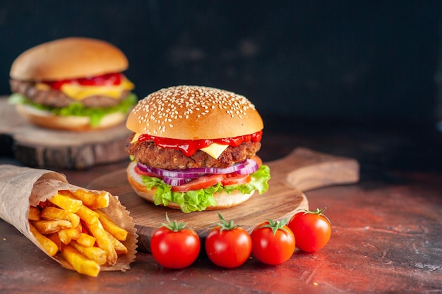 Widok z przodu pyszne mięso cheeseburger z frytkami na ciemnym tle obiad burger fast-food kanapka tostowa sałatka danie