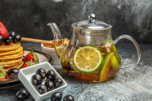 Widok z przodu pyszne naleśniki z oliwkami i czajnik z herbatą na lekkiej powierzchni owoce